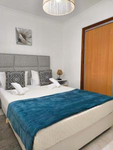 een slaapkamer met een groot bed met een blauwe deken bij ManelMar O Refúgio in Nazaré