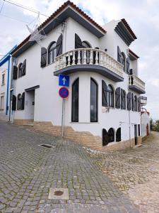 een wit gebouw met een balkon in een straat bij ManelMar O Refúgio in Nazaré +14 foto's