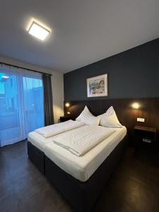 een slaapkamer met een groot bed met witte lakens bij Ayhan Hotel in Burgdorf