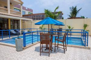 une table et des chaises avec un parasol à côté d'une piscine dans l'établissement Alojamento Local - Amor e Mar, à Luanda