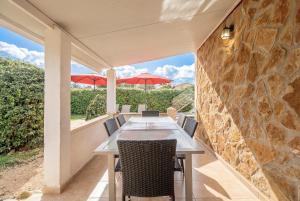 a patio with a table and chairs and a stone wall at Es Marroig Villa y Spa in Llucmajor