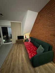 a living room with a green couch and a brick wall at Apartament Green Powiśle in Kwidzyn