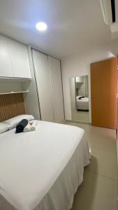 une chambre avec un grand lit blanc et une salle de bain dans l'établissement Apartamento em Resort no Litoral sul, à Parnamirim