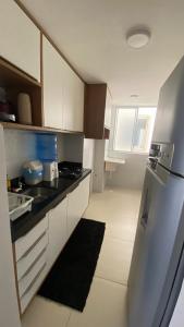 une cuisine avec des armoires blanches et un réfrigérateur en acier inoxydable dans l'établissement Apartamento em Resort no Litoral sul, à Parnamirim