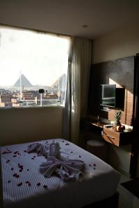 a bedroom with a bed and a large window at Makan Pyramids Hotel in Cairo