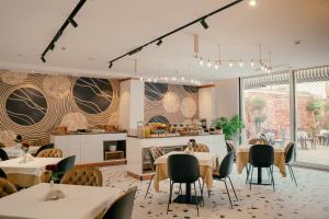 a dining room with tables and chairs and windows at Moenia Boutique Hotel in Durrës