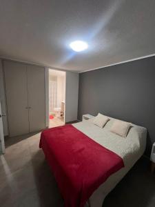 een slaapkamer met een groot bed met een rode deken bij Departamento claro solar in Temuco