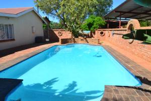 una grande piscina blu accanto a un muro di mattoni di Hadida Guest House a Kimberley