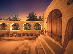 NarCappanar Cave Hotel的一座带木门和一些盆栽植物的建筑