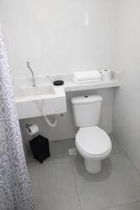 een witte badkamer met een toilet en een wastafel bij Aconchego do mar in Rio das Ostras +3 foto's