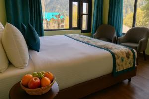 a bedroom with a bed with a bowl of fruit on a table at The Frozen Leaf in Pahalgām