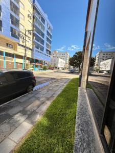 a street with a car parked next to a building at Apto no centro - Praça Mini Golf - Sacada - Garagem - 300m do Mar - Térreo in Capão da Canoa