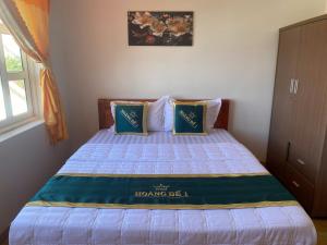 a bed with two blue pillows on top of it at Motel hoàng đế 1 in Chau Doc