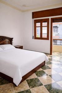 a bedroom with a large white bed and a window at Villa abdo in Asilah
