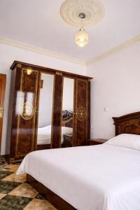 a bedroom with a white bed and a mirror at Villa abdo in Asilah