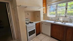 a small kitchen with a stove and a sink at Griffin lakeside in Yarralumla