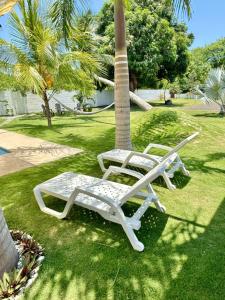 Twee witte stoelen staan op het gras bij een palmboom. bij Casa Doral Monterrico in Monterrico