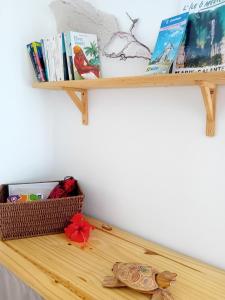 ein Holzregal mit Büchern und einem Korb darauf in der Unterkunft Studio vue mer avec cuisine et SDB in Capesterre