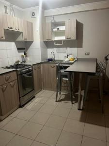 a kitchen with wooden cabinets and a table with chairs at Departamento Puertas del Mar in La Serena