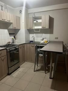 a kitchen with wooden cabinets and a table in it at Departamento Puertas del Mar in La Serena