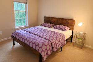 een slaapkamer met een bed met een paars dekbed en een raam bij Private room with a private full bathroom in Woodbridge