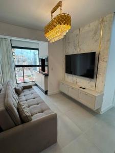 un salon avec un canapé et une télévision à écran plat dans l'établissement Luxuoso Doce lar com Garagem, à Itapema