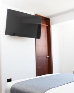 een slaapkamer met een bed en een flatscreen-tv aan de muur bij Hostal Llampayec in Chiclayo