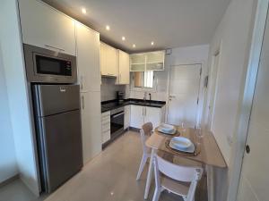 a kitchen with white cabinets and a wooden table with chairs at Oliva Home in Los Cristianos