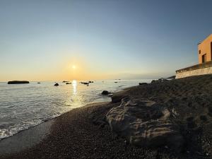 a beach with the sun setting over the water at Smile House Akiya in Hayama