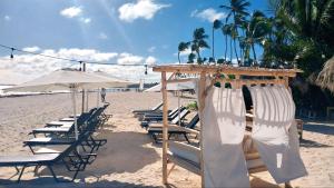 eine Gruppe von Stühlen und Sonnenschirmen an einem Strand in der Unterkunft Beach Lounge Suites Punta Cana 1 in Punta Cana