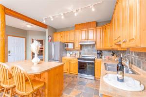 a kitchen with wooden cabinets and a table and chairs at Snowy Creek Chalet in Big White