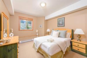 a bedroom with a large white bed and a window at Snowy Creek Chalet in Big White