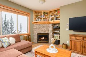 a living room with a fireplace and a television at Snowy Creek Chalet in Big White