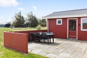 een patio met een tafel en stoelen naast een rood gebouw bij 421-Thisted-Fiskervej-147 in Nørre Vorupør