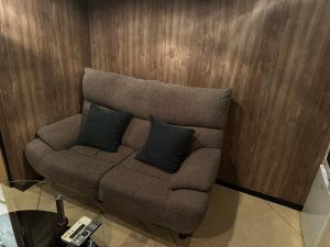 een bruine bank met twee zwarte kussens erop bij ホテルemoemo in Fuchu