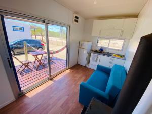 a living room with a blue couch and a kitchen at La Fresa glamping in Punta Del Diablo