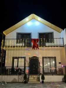 een huis versierd met kerstlichtjes en een rode strik bij Ramalin evi in Quba