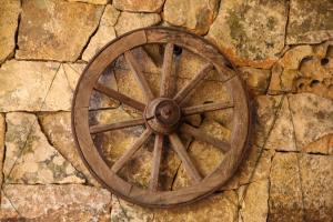 an old wooden wagon wheel on a stone wall at Hotel Lu Pitrali in San Teodoro