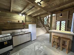 a kitchen with white appliances and wooden walls at pousada Aroeira, G Embaú in Palhoça