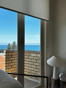 een slaapkamer met een groot glazen raam met uitzicht op de oceaan bij Beach & Ocean View Apartments Tamarama in Sydney