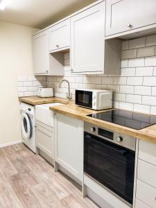 una cucina con armadietti bianchi ed elettrodomestici bianchi di Cozy home a Kings Lynn