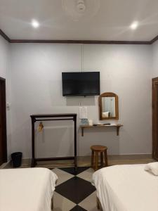 琅勃拉邦Sabai Sabai Backpackers Hostel的一间有两张床和一台挂在墙上的电视的房间