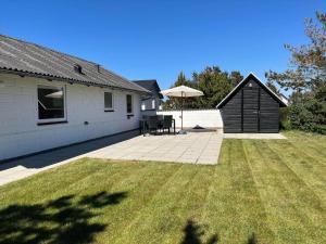 un cortile di una casa con un patio e un ombrellone di 895-Thisted-Kuttervej-5 a Thisted