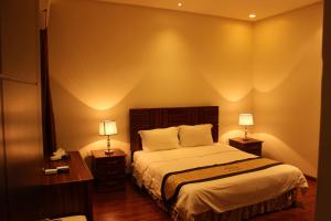 1 dormitorio con 1 cama y 2 mesitas de noche con lámparas en Nozol Aram 3 Hotel Apartments, en Riad