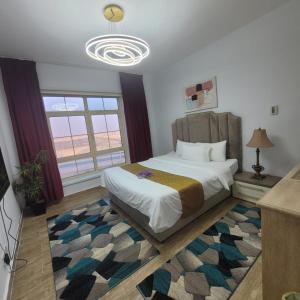 een slaapkamer met een bed met een tapijt en een kroonluchter bij Sun Rose Apartment in King Abdullah Economic City +9 foto's