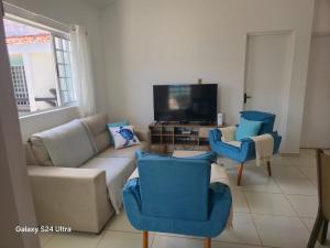 a living room with a couch and chairs and a tv at Flat aconchegante em Itamaracá in Itamaracá