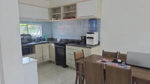 a kitchen with white cabinets and a table with chairs at Flat aconchegante em Itamaracá in Itamaracá