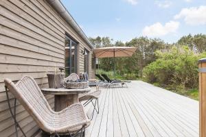 a wooden deck with chairs and an umbrella at 157-Thisted-Isfuglevej-17 in Thisted