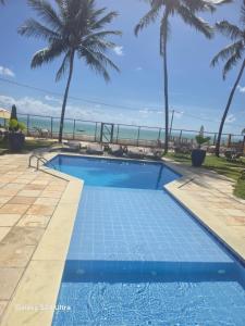 a swimming pool with the ocean in the background at Flat aconchegante em Itamaracá in Itamaracá