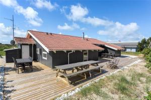 une maison dotée d'une terrasse en bois avec une table et des bancs dans l'établissement 975-Thisted-Klitstien-45, à Torsted